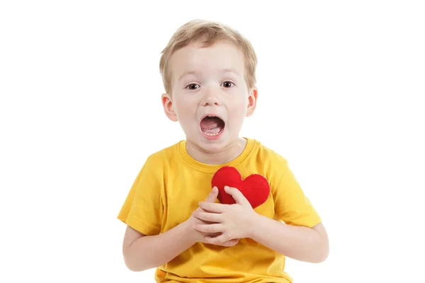 Улыбающийся мальчик с фигуркой красного сердца. Символ любви, семьи. Концепция семьи и детей . — стоковое фото