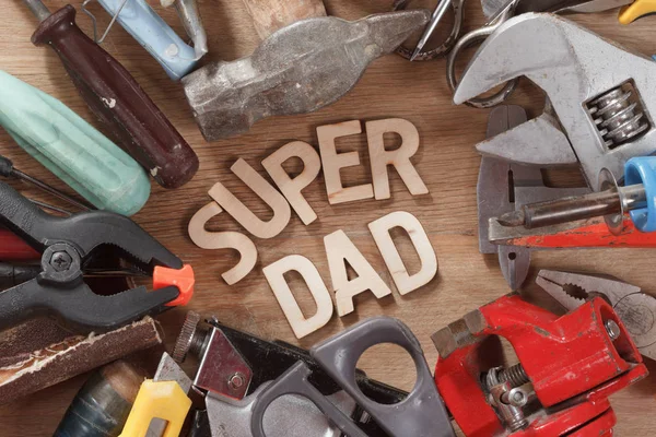 Fathers day concept. Set of old tools on a wooden carpenter desk with Super Dad text. Happy holiday.