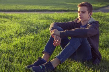 Parkta çim akıllı telefon üzerinden müzik dinleme genç adam.