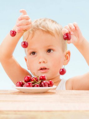 Kırmızı meyveler ile çocuk, çocuk yiyor ve kiraz seçer.