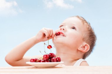 Kırmızı meyveler ile çocuk, çocuk yiyor ve kiraz seçer.