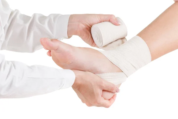 Doctor rewinds a foot bandage to a young man. — Stock Photo, Image