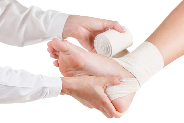 Doctor rewinds a foot bandage to a young man. — Stock Photo, Image