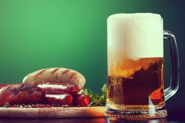Bir fincan yeşil zemin üzerine ızgara sosis birayla. Oktoberfest içecek ve gıda