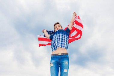 ABD bayrağı bir yaz gökyüzü arka planda çalışan bir adam tarafından düzenlenmektedir