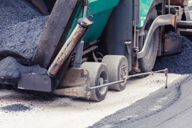 Finişer yeni asfalt yolda yapar.