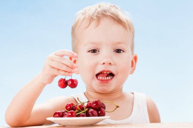 Kırmızı meyveler ile çocuk, çocuk yiyor ve kiraz seçer.