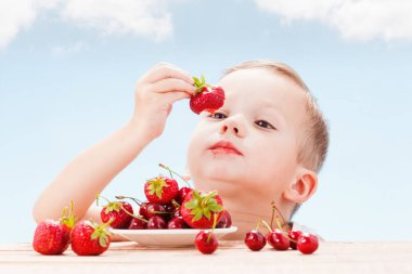 Kırmızı meyveler ile çocuk, çocuk yiyor ve kiraz seçer.