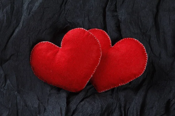 Red hearts shape toys on black paper background