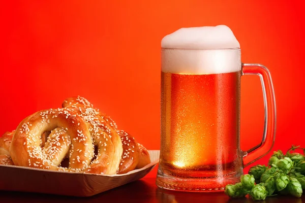 Cerveza artesanal Octoberfest con pretzel y lúpulo sobre fondo rojo . —  Fotos de Stock