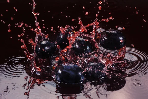 Червоний сік або винний сплеск з виноградною ягодою крупним планом . — стокове фото