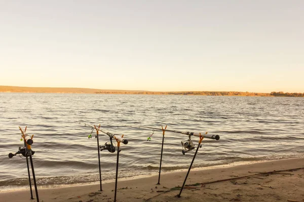 Cañas de pescar y artes de pesca en la orilla del río, costa del lago . — Foto de Stock