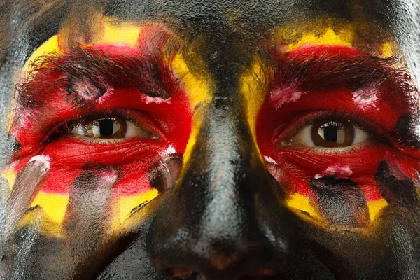 Eyes of German or Belgian sports fan patriot. Bandera de país pintada en la cara del hombre . —  Fotos de Stock