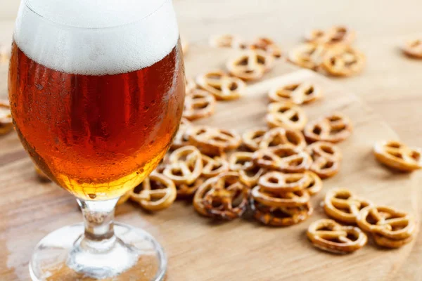 Copo de cerveja espumosa fria com pretzel alemão — Fotografia de Stock