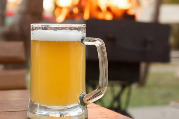 Un vaso de cerveza en el fuego de fondo en la parrilla — Foto de Stock