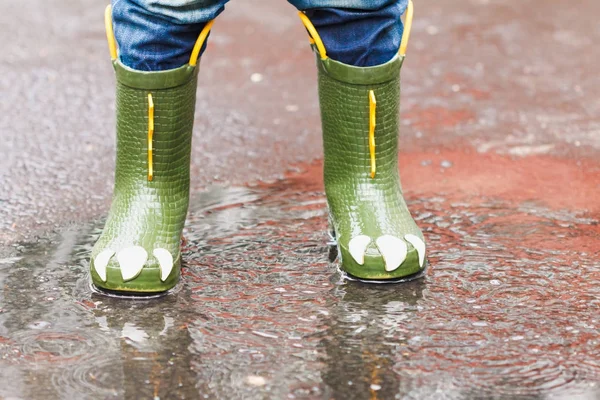 Enfant avec des bottes de pluie saute dans une flaque — Photo