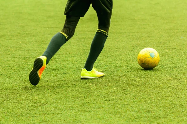 Jogador de campo para a frente com uma bola no campo de futebol central . — Fotografia de Stock