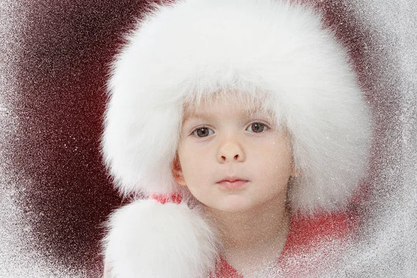Счастливого Рождества маленькому грустному ребенку в окне, смотрящему на зиму. Малыш и снегопад . — стоковое фото