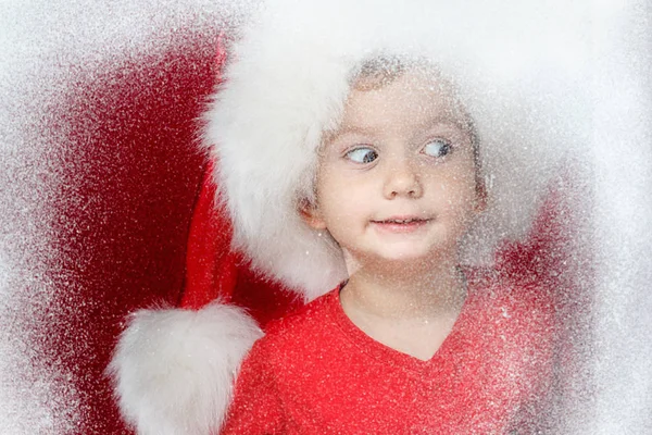 Criança de Natal feliz na janela olhando para o inverno. Criança e queda de neve . — Fotografia de Stock