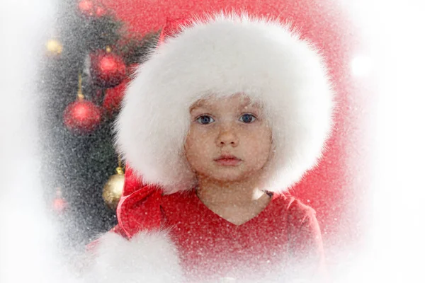 Criança em Santa cap com árvore de Natal na janela olhando para o inverno. Criança e queda de neve . — Fotografia de Stock