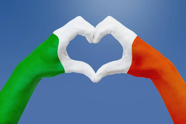 Drapeau des mains d'Irlande, forme un cœur. Concept de symbole de pays, sur ciel bleu . — Photo