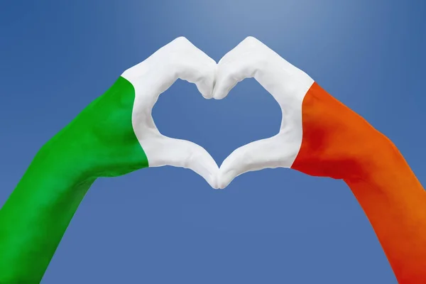 Ręce flaga Irlandii, kształt serca. Pojęcie symbol kraju, na błękitne niebo. — Zdjęcie stockowe