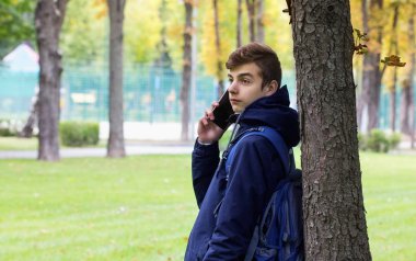 Telefonu konuşurken bir akıllı telefon ile Tenager adam portresi. Park açık.