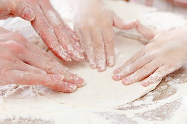 Anne ve çocuk elleri un ile hamur ekmek veya pizza için hazırlar. Fırın arka plan.