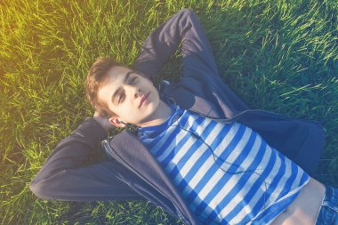 Genç adam müzik listeleme çim üzerinde yalan