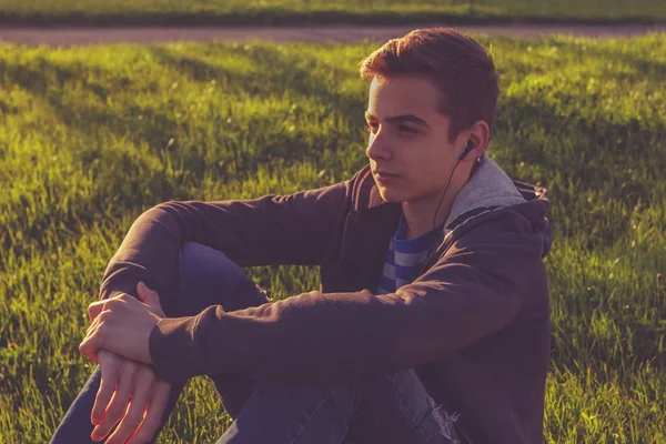 Young man sitting on the grass listing music