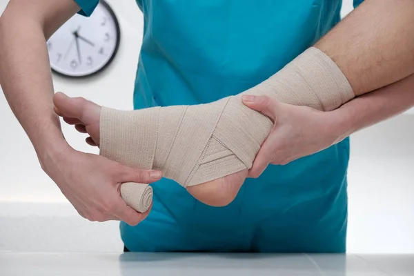 Närbild av manliga läkare bandage foten av kvinnlig patient — Stockfoto