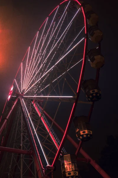 Park rozrywki w nocy - widok z diabelskim młynem, karuzele i atrakcji w ruchu — Zdjęcie stockowe