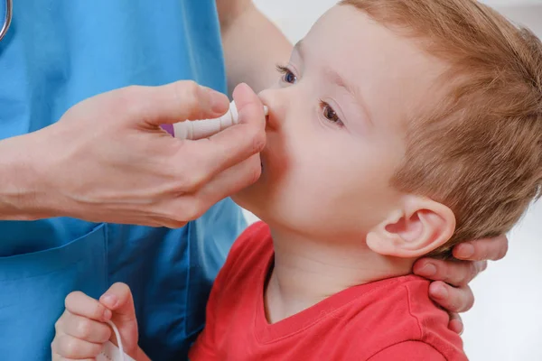 Barnläkare kvinna, kid pojke med nässpray — Stockfoto
