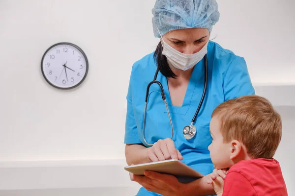 Läkare med stetoskop och tablett prata med pojken patienten på vit bakgrund. — Stockfoto