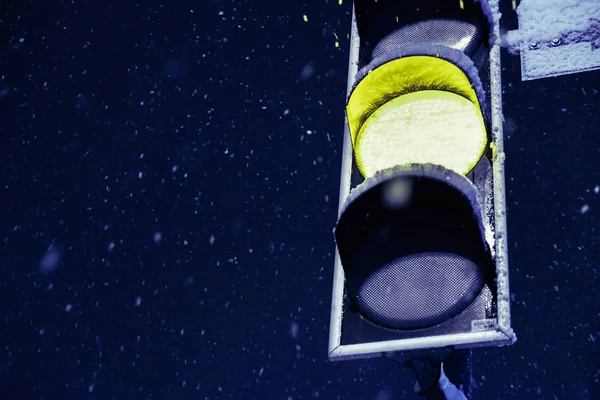 在大城市里多雪的冬天, 雪花映衬着黄色的红绿灯信号。关闭视图. — 图库照片