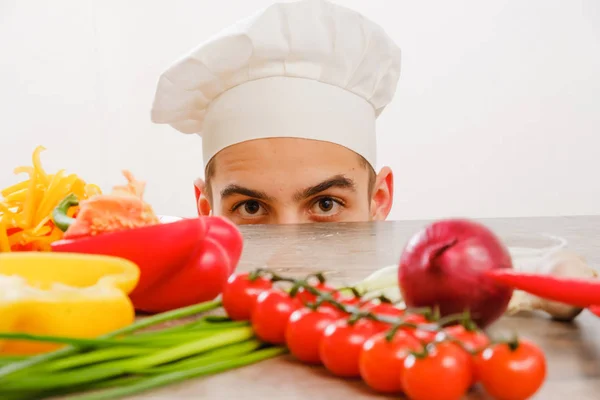 Człowiek z WPR kucharz na białym tle. Szef kuchni z warzywami na stole. Kucharz z wesołą twarz w twarz z bliska. — Zdjęcie stockowe