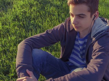 genç çocuk telefon ile çim üzerinde yalan
