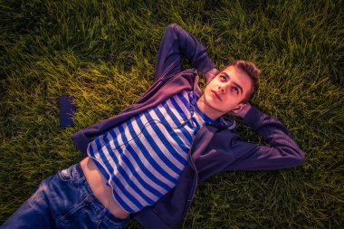 genç çocuk telefon ile çim üzerinde yalan