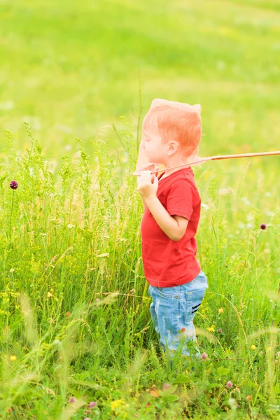 Adorable niño caucásico jugando con la cuchara-red en el prado en verano cálido y soleado o día de primavera . — Foto de Stock