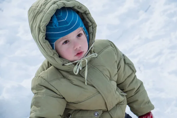 Счастливый ребенок в зимней одежде смеется во время игры в снегу — стоковое фото