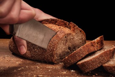 Şef bütün taze kokulu ekmek bıçağı ile masaya keser. Gıda kavramı buğday pasta kesme tahtası üzerinde