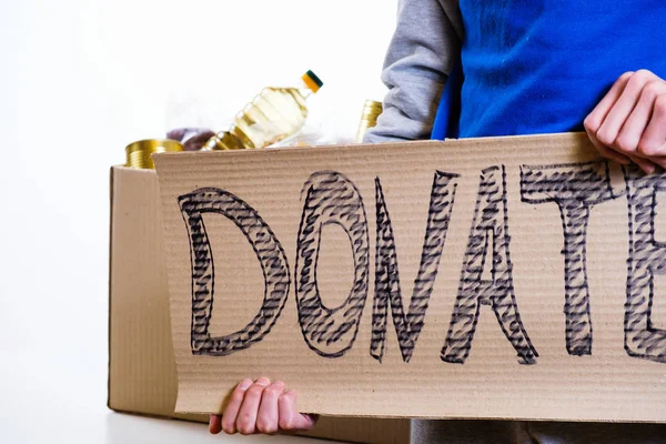 Pobre hombre sin hogar sosteniendo cartón con comida de palabra DONAR — Foto de Stock