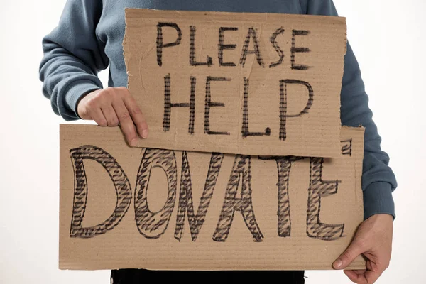 Бездомний бідний чоловік тримає картонну дошку зі словом Будь ласка, допоможіть, DONATE — стокове фото