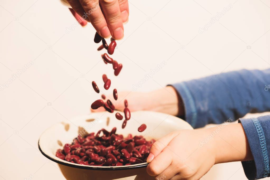 Small hungry child gets food donate help a volunteer, with bowl full of beans