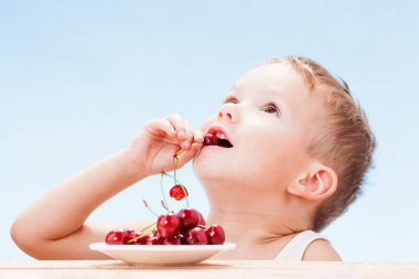 Kırmızı meyveler ile çocuk, çocuk yiyor ve kiraz seçer.