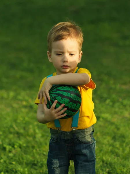 かわいい肯定的な子供は、緑の草原の上にボールと楽しく遊んで — ストック写真
