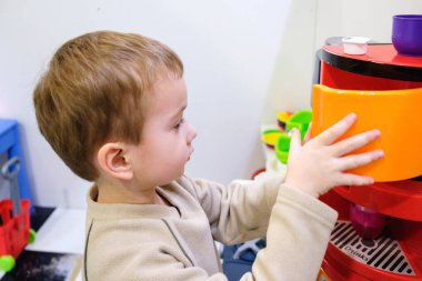 Çocuk odası ya da anaokulu içinde oyuncak mutfak oynayan çocuk