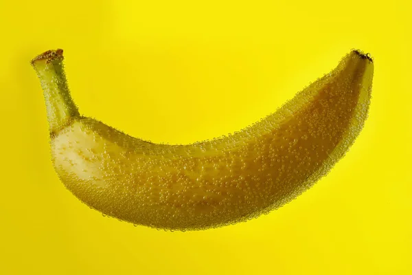 Banane tombant dans l'eau avec des gouttes sur jaune — Photo