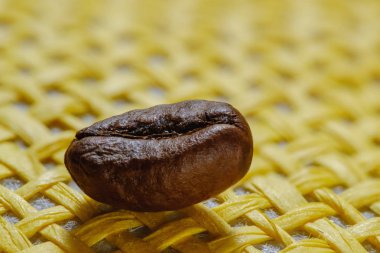 Taze kavrulmuş makro kahve çekirdekleri, sarı hasır sepet arka plan kümesi.