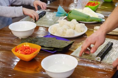 Geleneksel suşi yemek alır. Çocuk aşçı olarak giyinmiş.